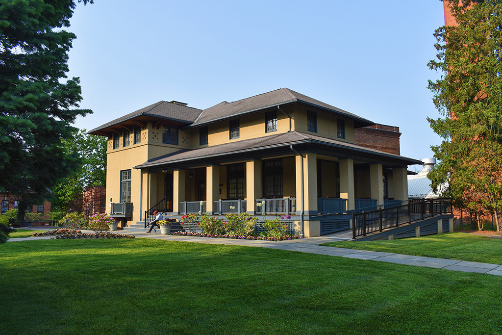 An exterior view of a Craftsman-style two-story house with a wide porch and a ramp.