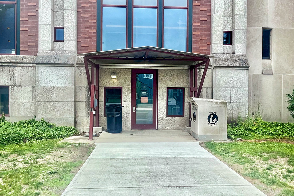 A building with a door and a trash can.
