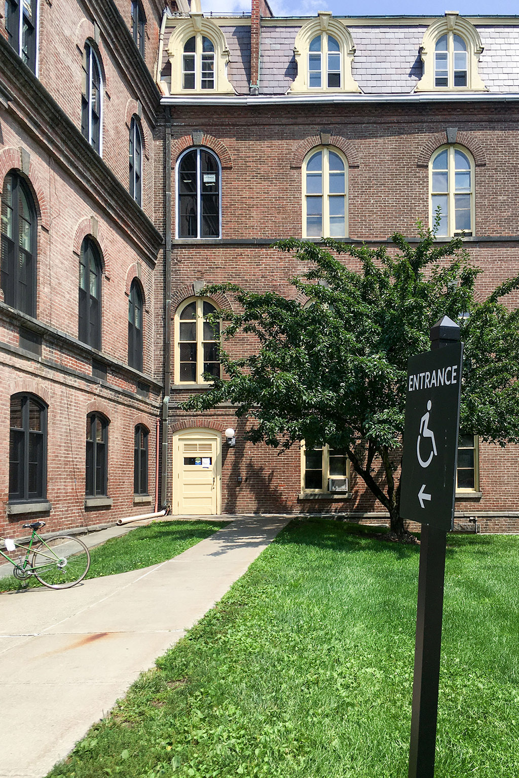 A sign, "Entrance" in front of a brick building.