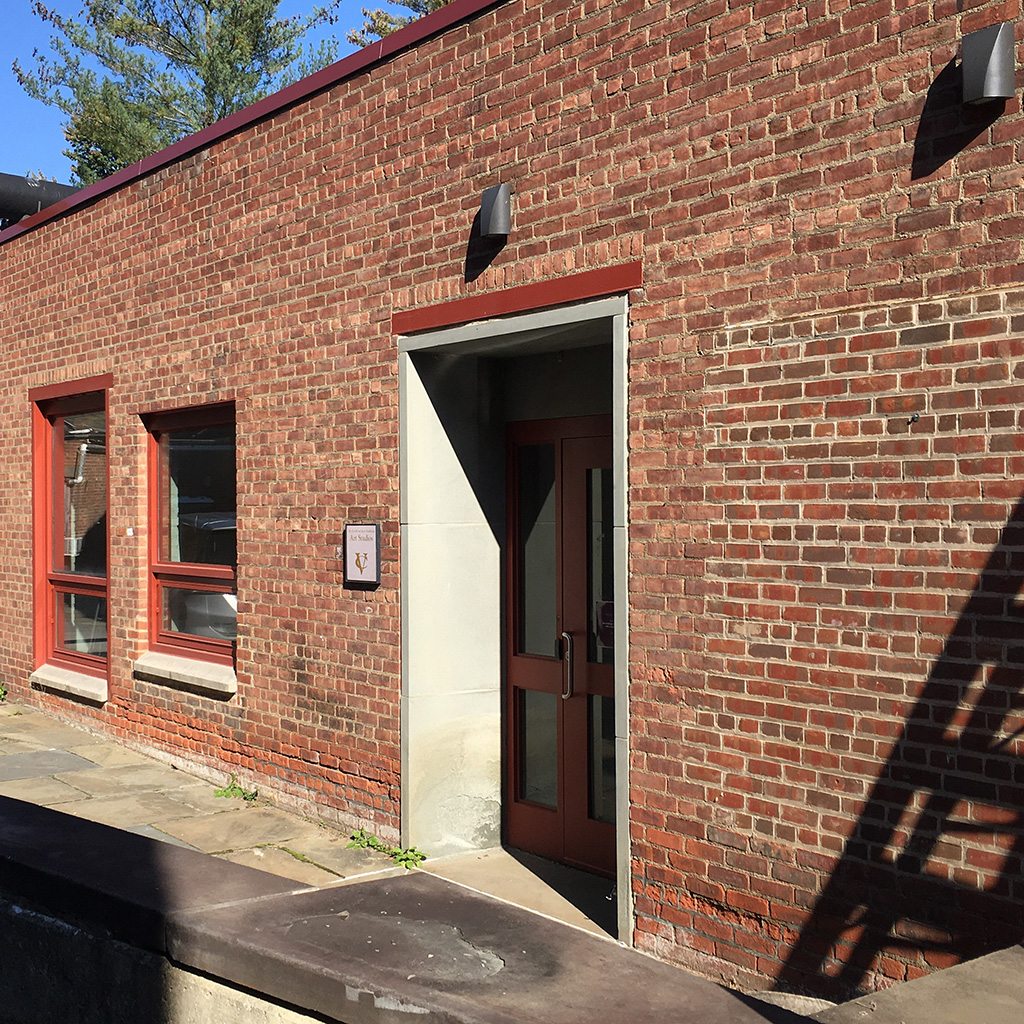 Exterior view of a single-story brick building with red-framed windows and a glass door, set against a clear blue sky.