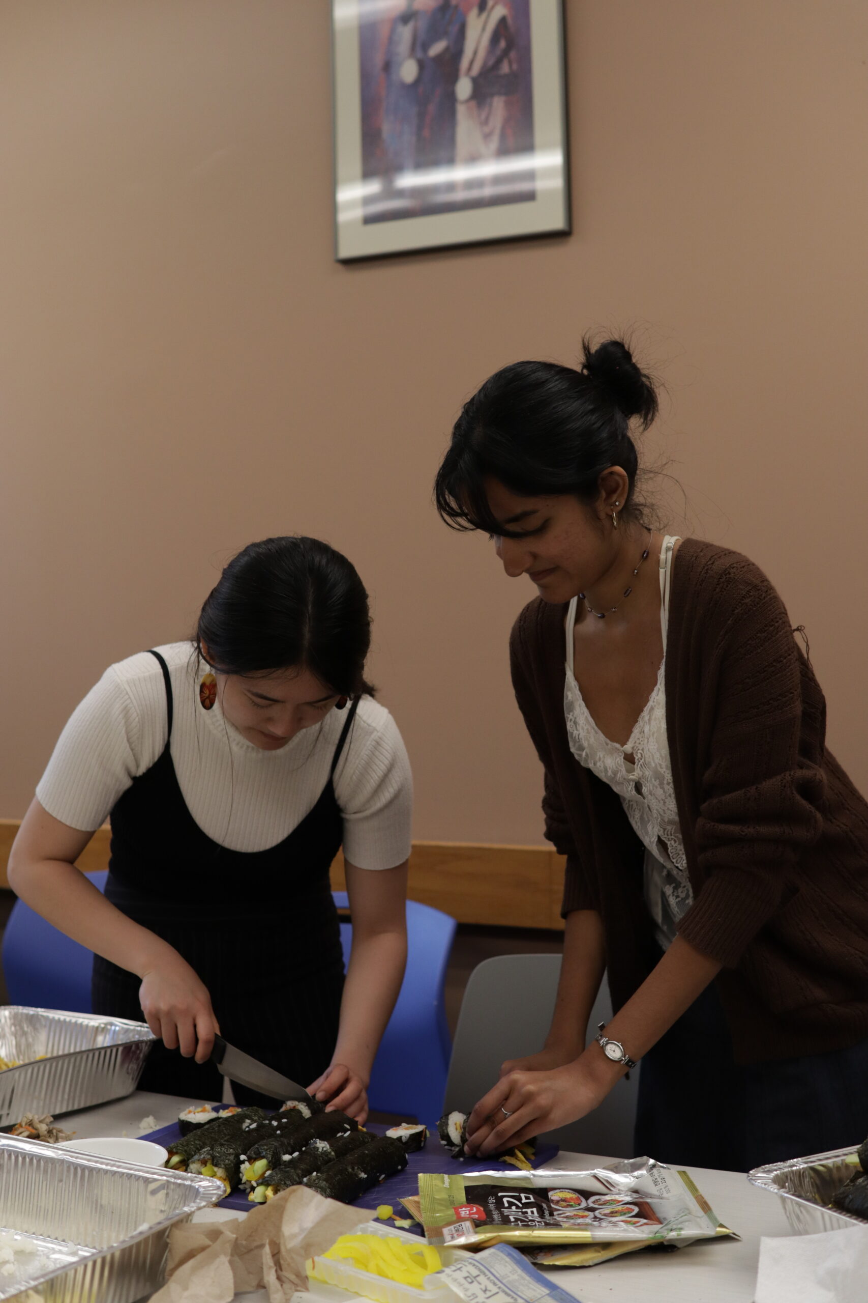 Students standing preparing meals in the ALANA Center Conference room in preparation for the AAPI Heritage Month Kick off. 