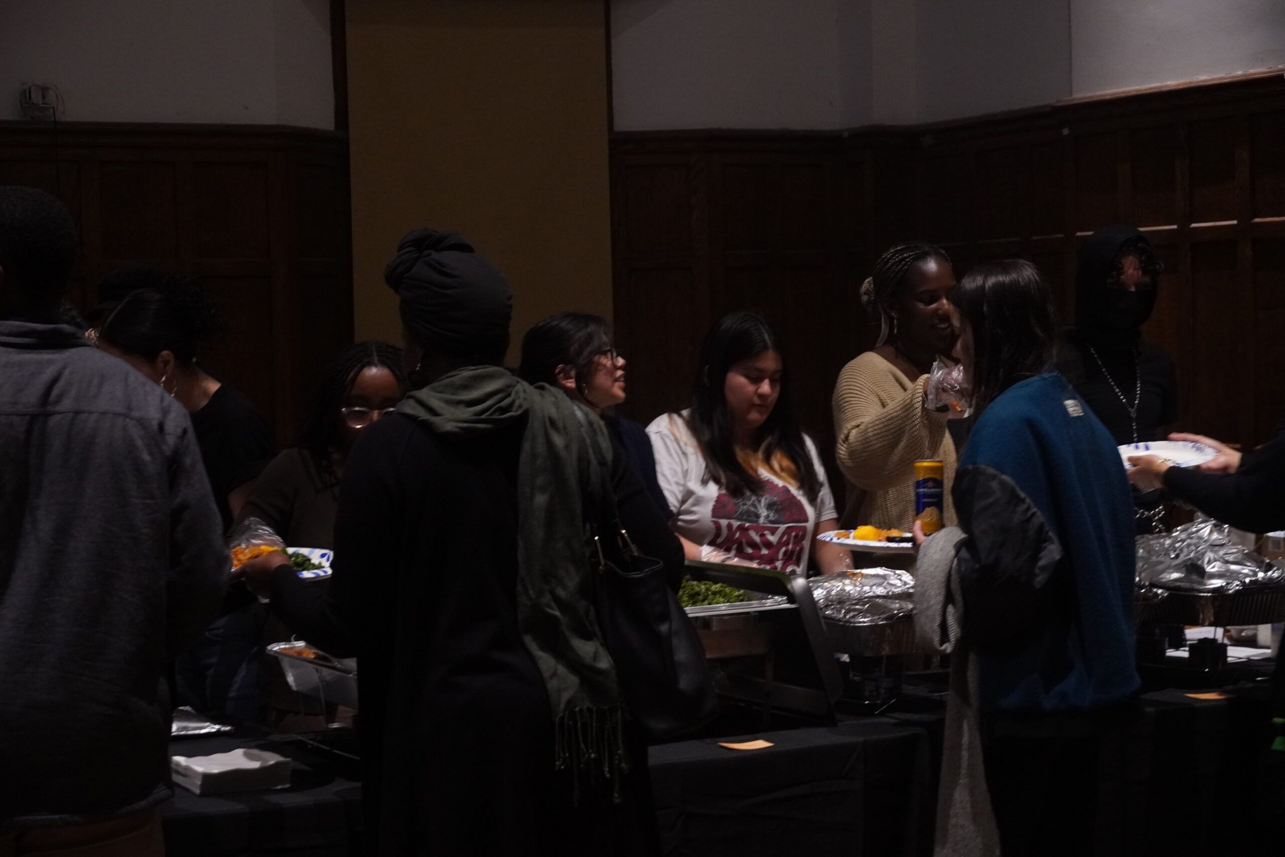Students standing parallel to attendees serving food.