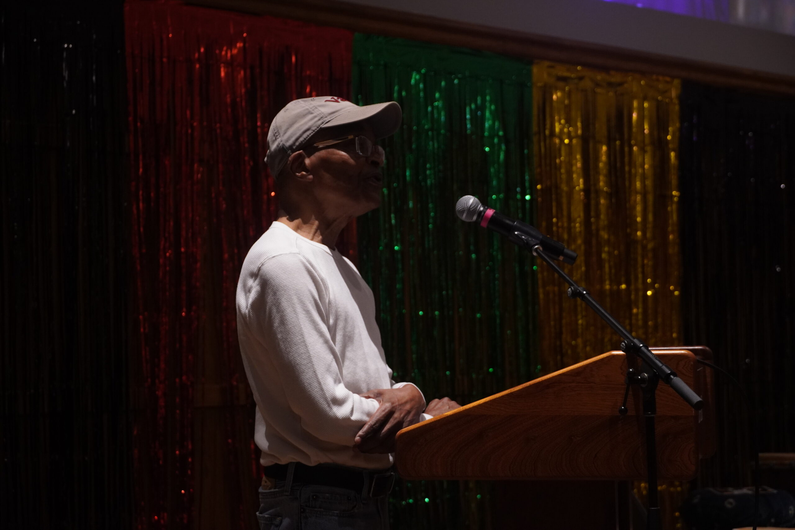 Eric Wilson '76 standing at the podium, talking into the mic and looking into the audience. 