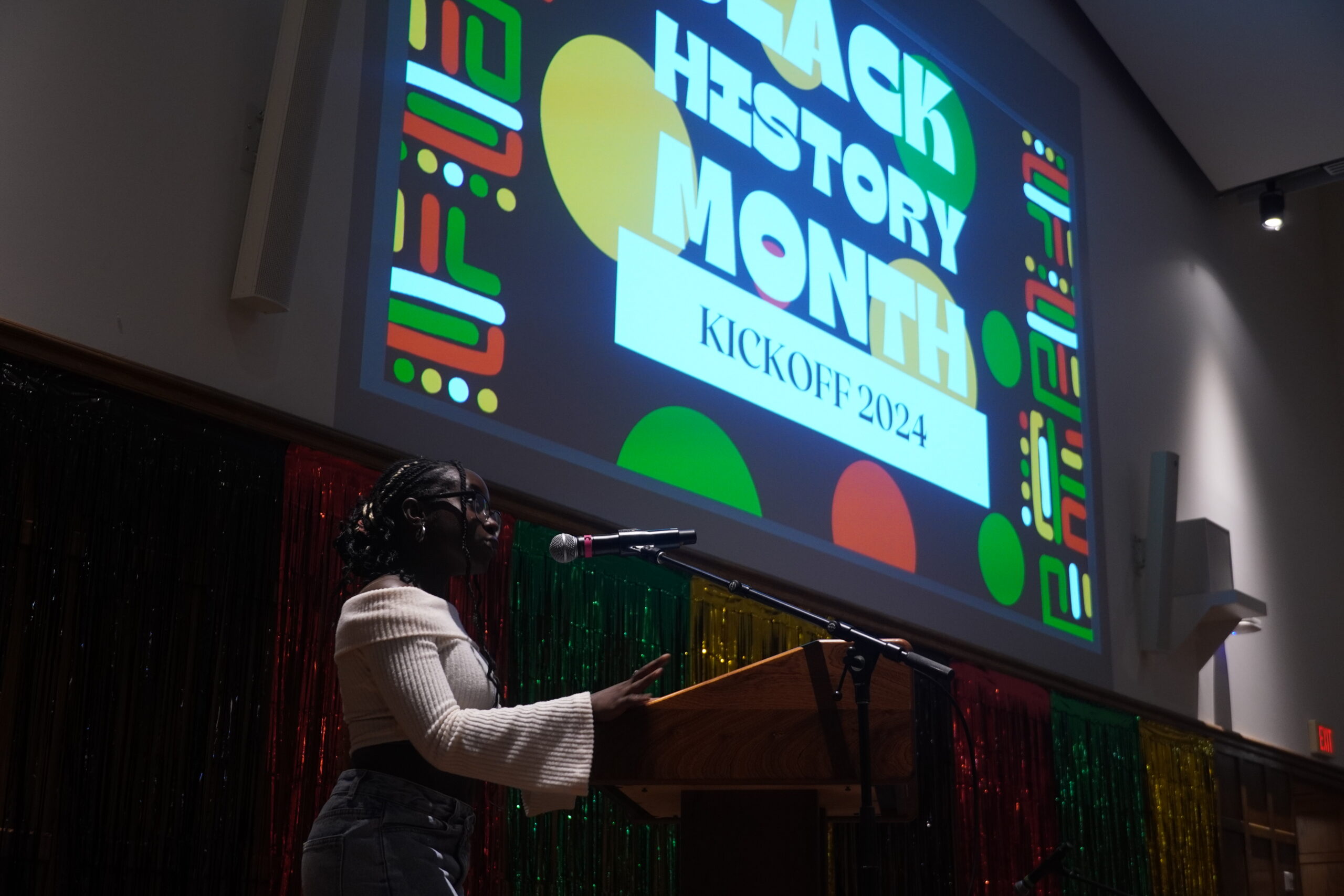 Shyasia Arnold standing at the podium, talking into the mic and looking into the audience. 