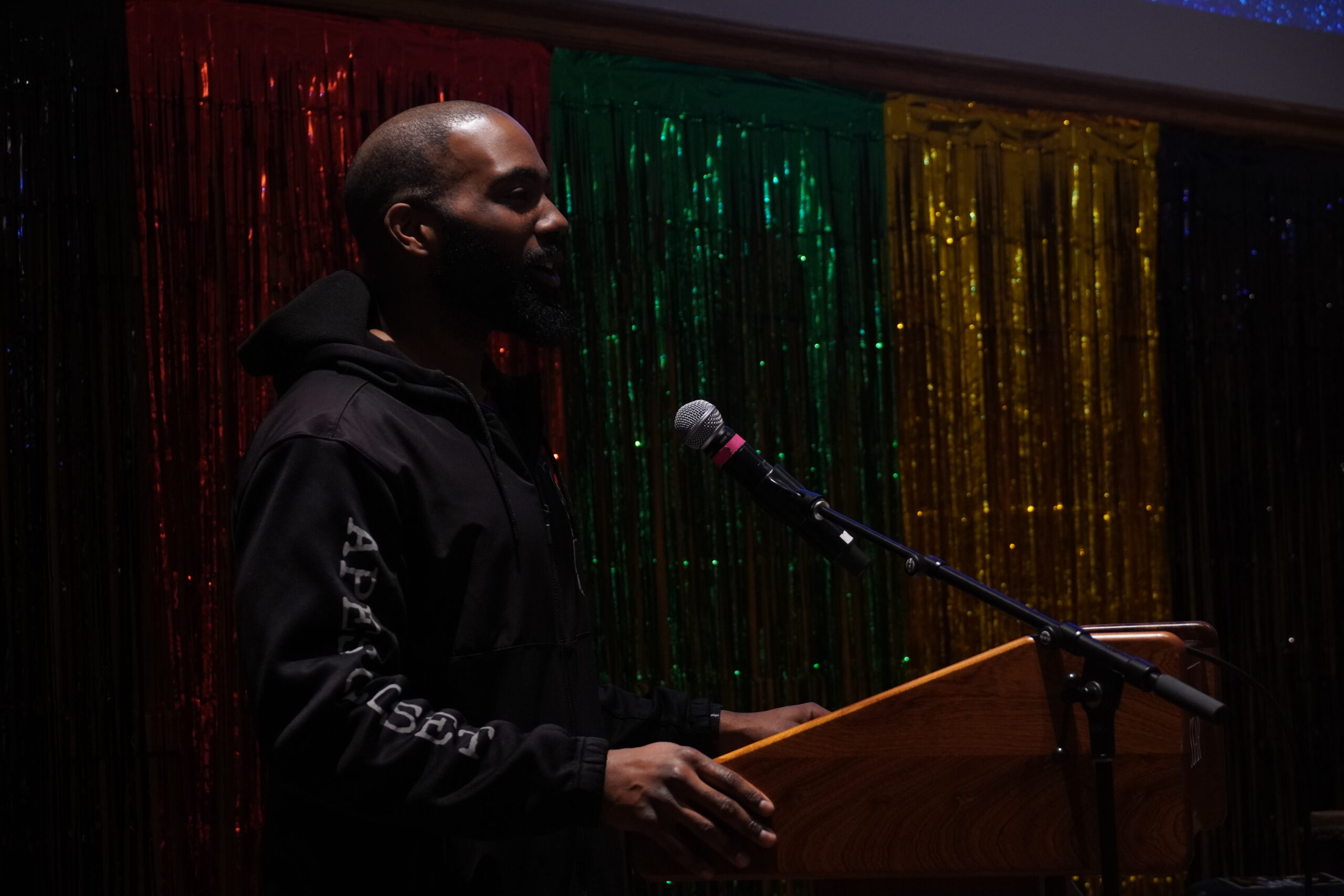 Dr. Ed Buie II is standing at the podium, talking into the mic and looking out into the audience. 