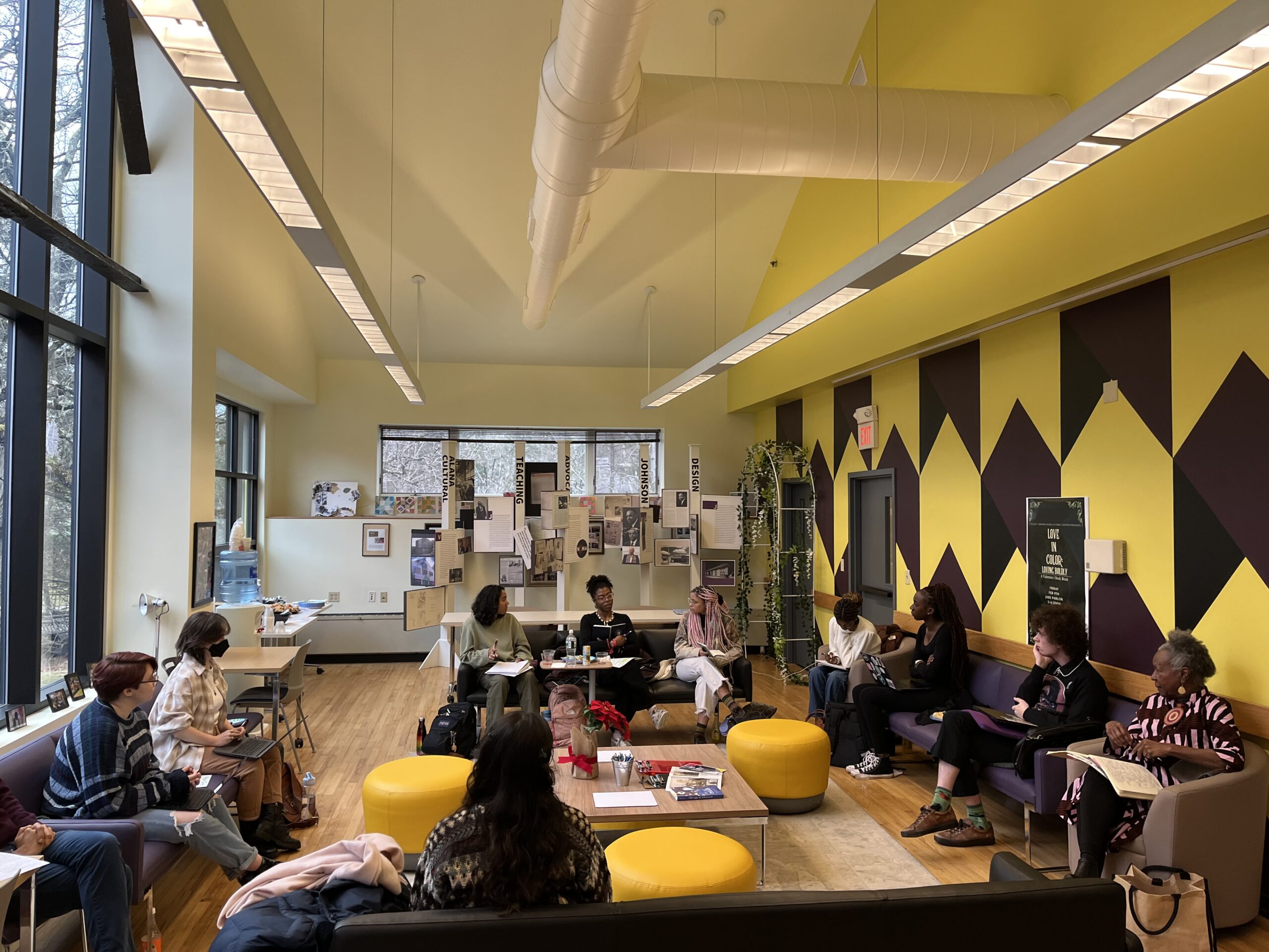 Students seated around the ALANA Community Room listening to each other recite their poems.