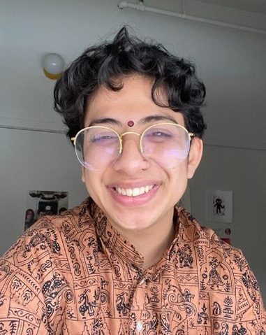 Kiran Rudra smiling at the camera while wearing glasses.