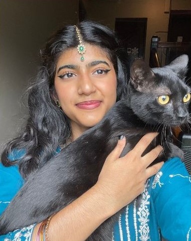 Student Rabiah Aziz smiling while taking a selfie with her cat.