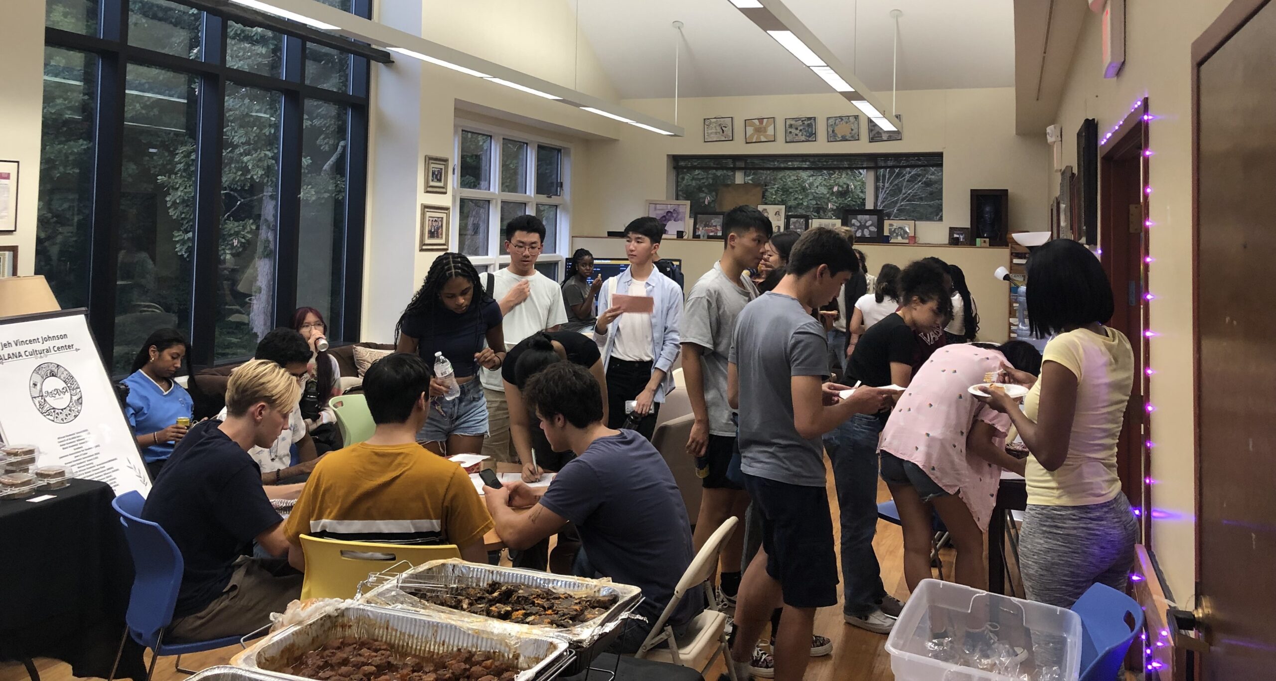 Group of students seated and standing in groups with beverages and food in their hands. 
