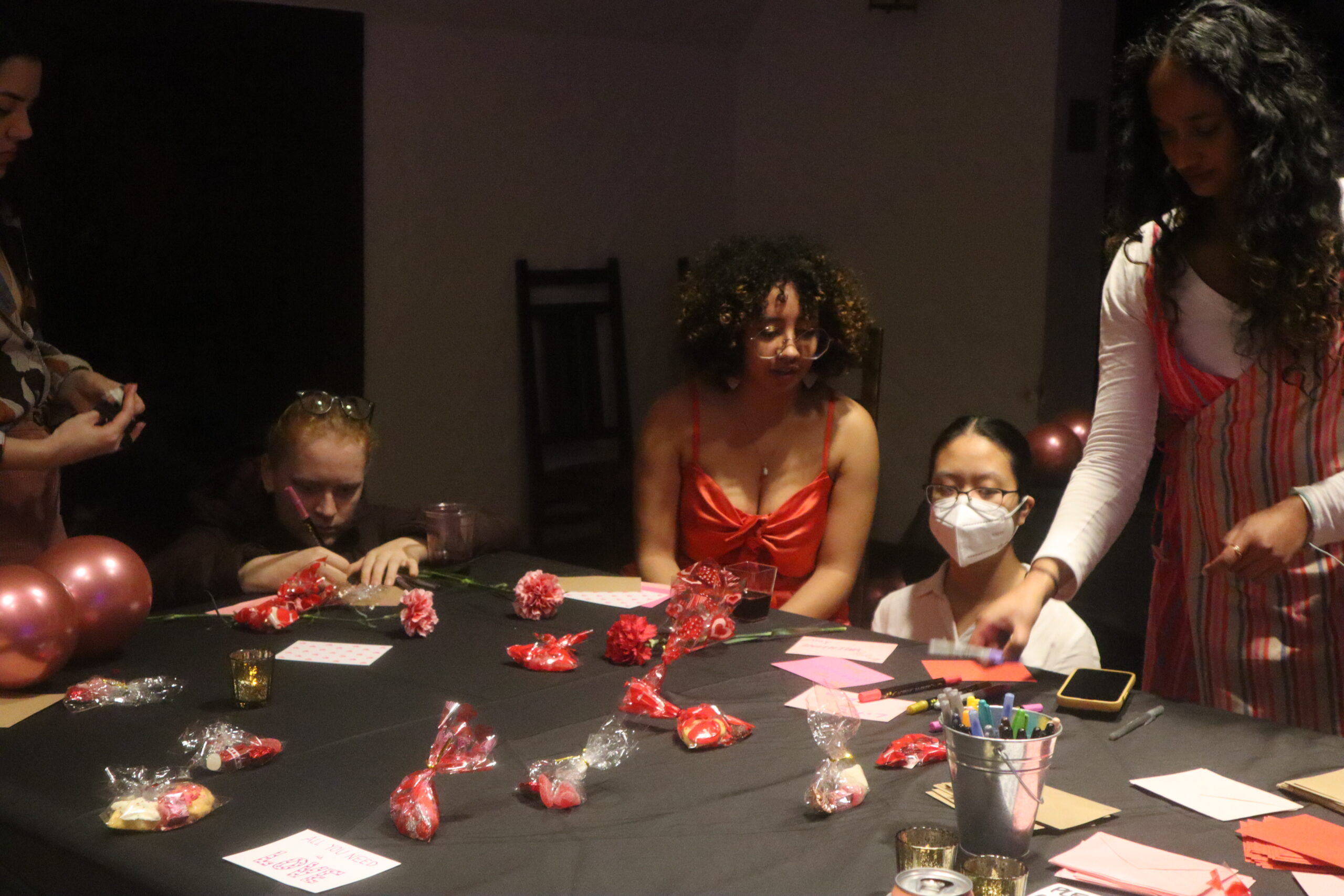 Five students around a table displayed with valentine's day crafts.