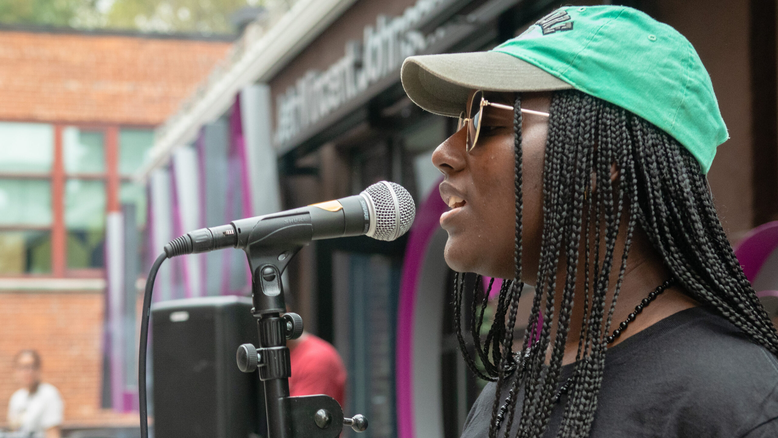 Mareme Fall '25, signing into the mic while standing in front of the ALANA Center.