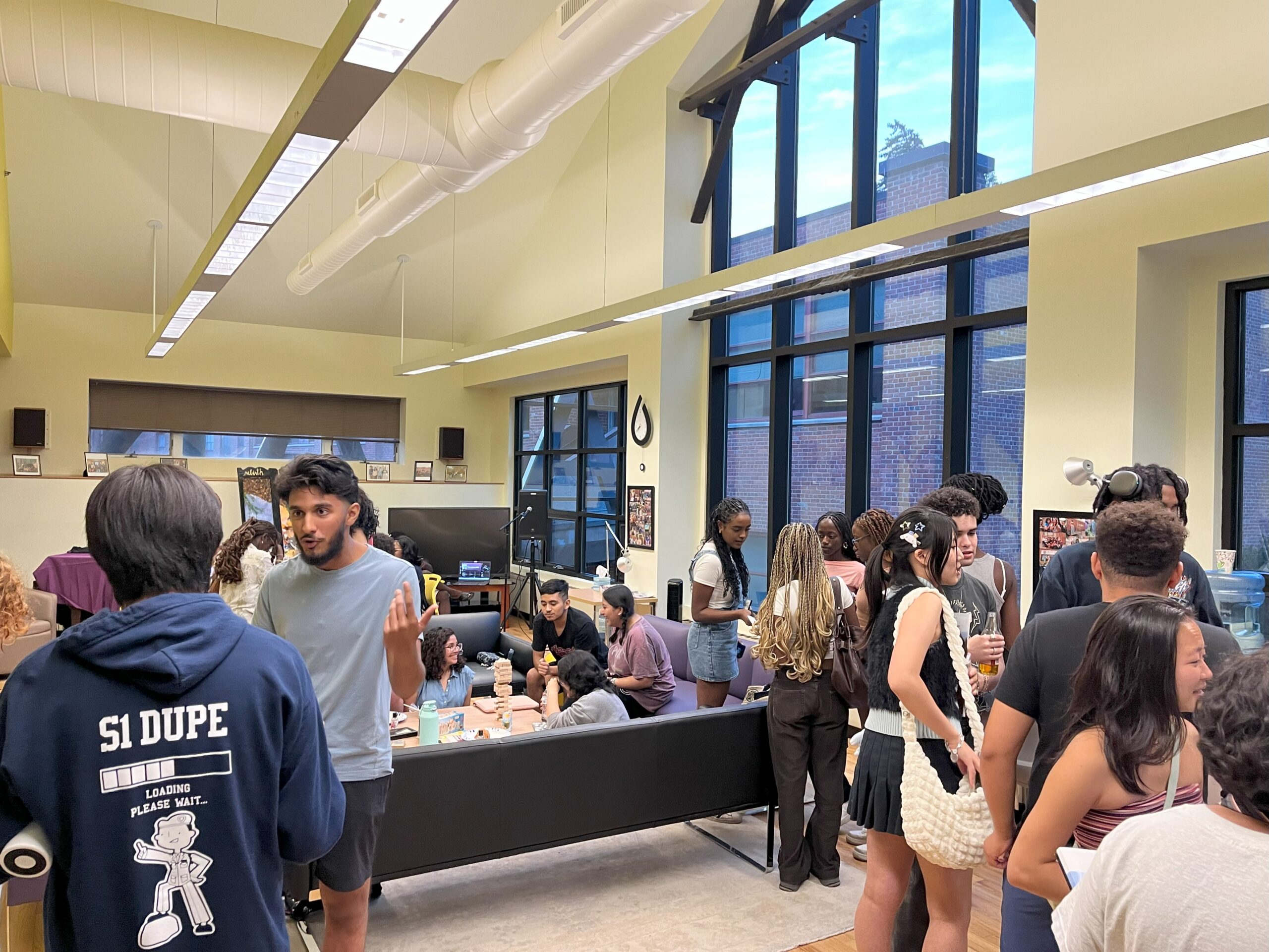 Student seated and standing in groups as they talk to each other throughout the community room.