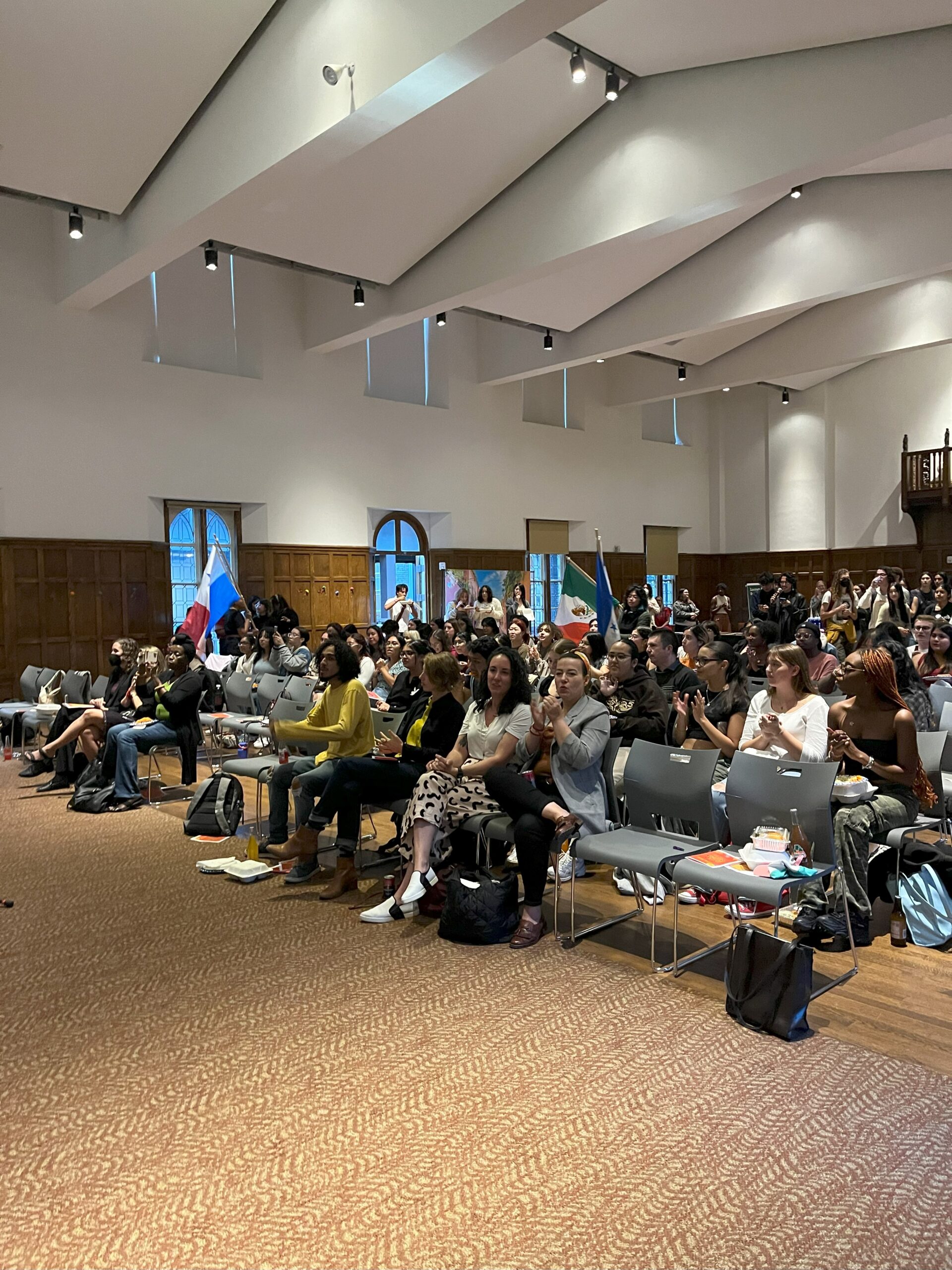 Large group of attendees seated in chairs side by side as they look towards the front of the stage.