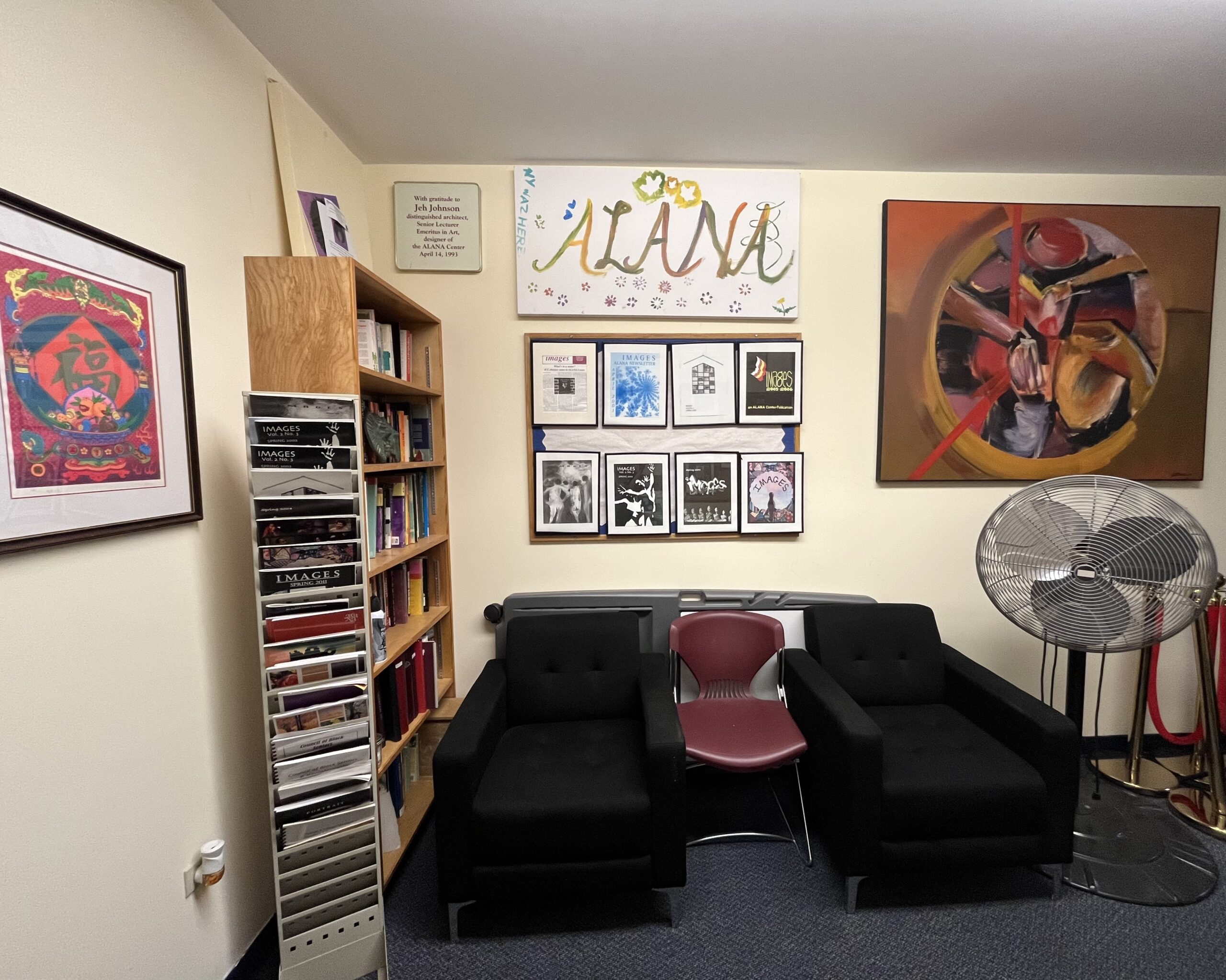 Two black solo cushion chairs side by side with a maroon plastic chair in the middle, wooden bookshelf with books, a canvas that says, "ALANA in various colors, a board with eight frames of the IMAGES covers, and a large metal fan.
