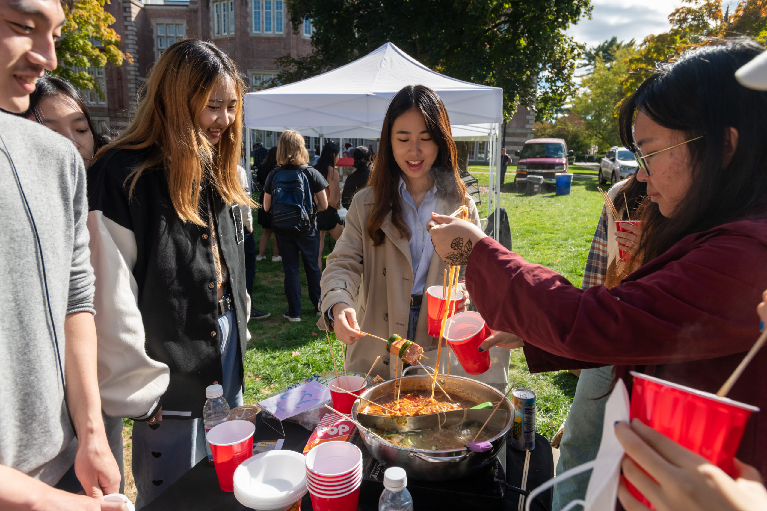 Students gathered around the CSC table at ALANA Fest cooking food.