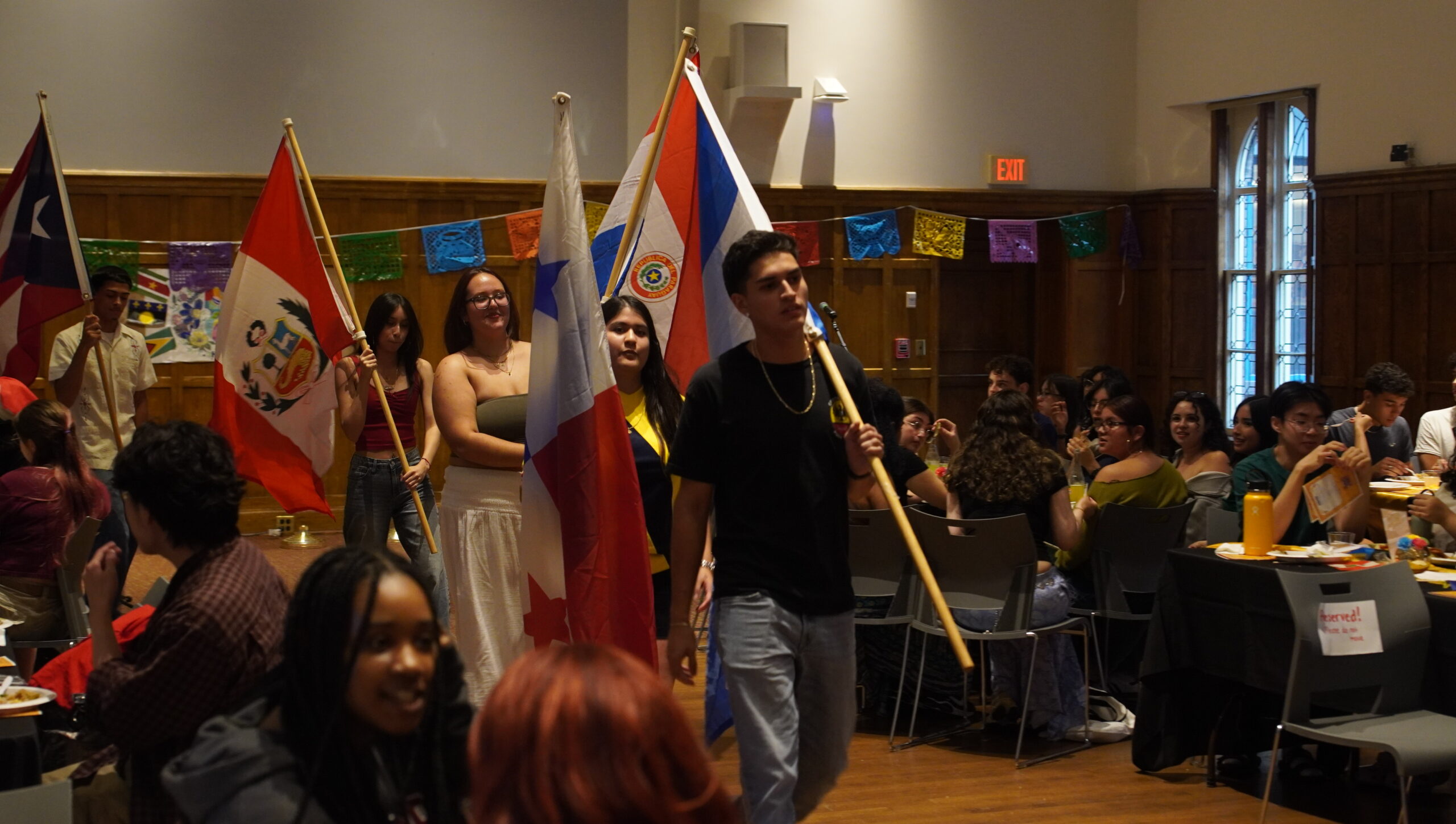 Students lining up for the flag ceremony. Four students pictured in the center frame of the image, standing each holding a different flag.