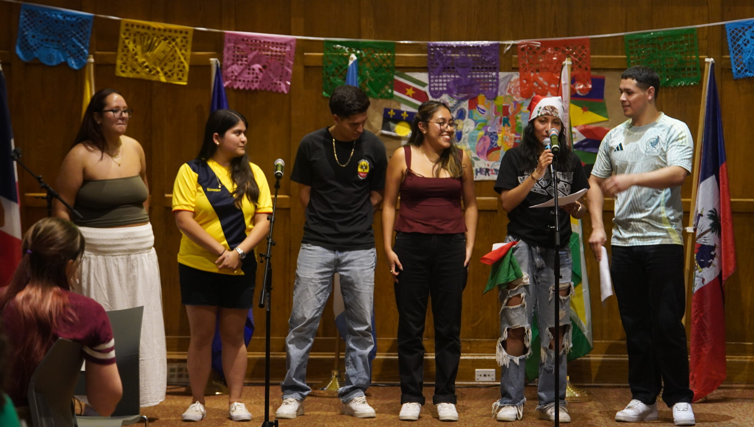 Six student leaders from LSU standing side by side in front of the audience as one student speaks into the mic.
