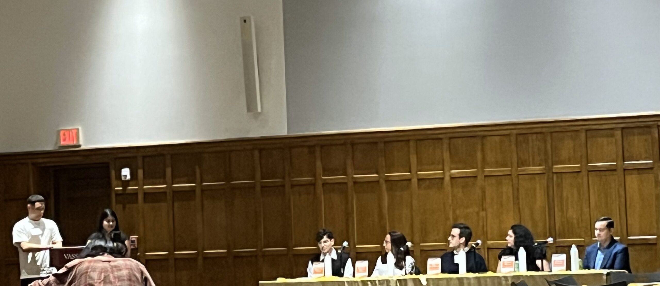 Two student leaders; the president and vice presidents of LSU are standing at the podium while five panelists are seated at two tables. 