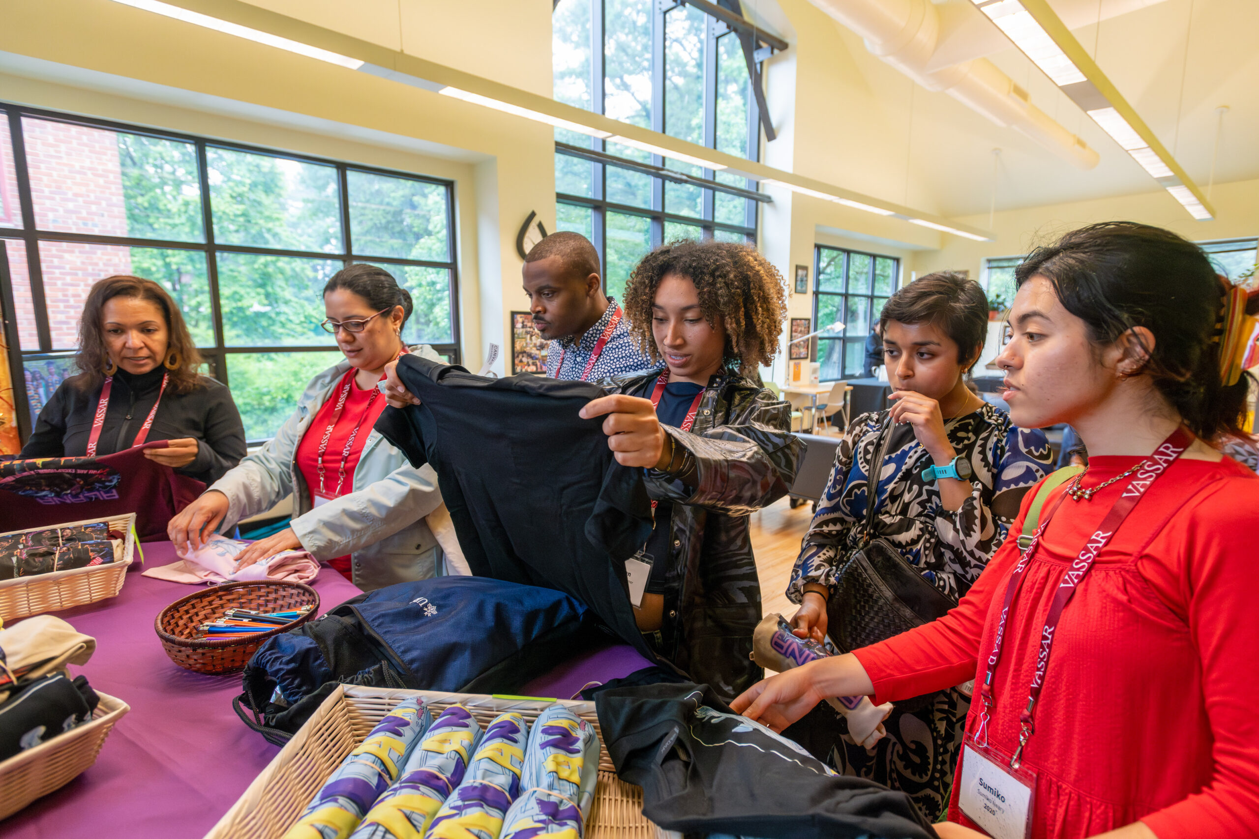 A group of six alums looking at ALANA shirts.