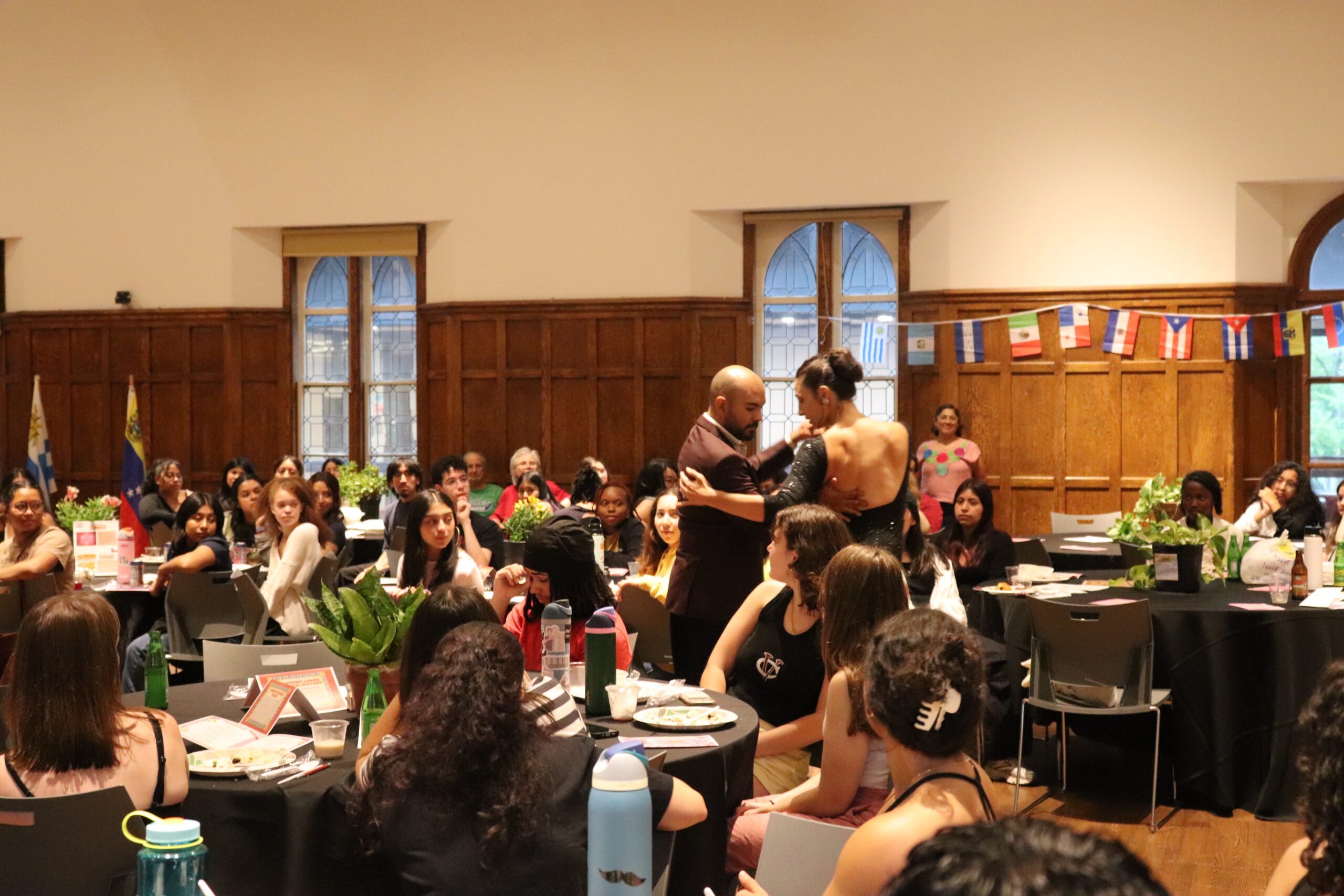 Room filled with people seated with at round tables while looking at the couple in the middle dancing