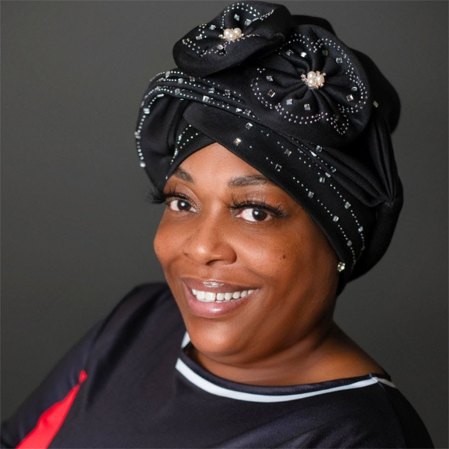 A head shot photo of Cathy with her body facing the left and her head posing towards the camera as she smiles brightly. 