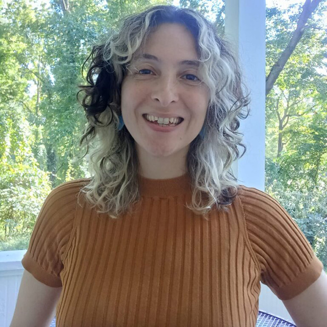 A photo of Montserrat facing the front of the camera as she smiles and wears a brown top. 