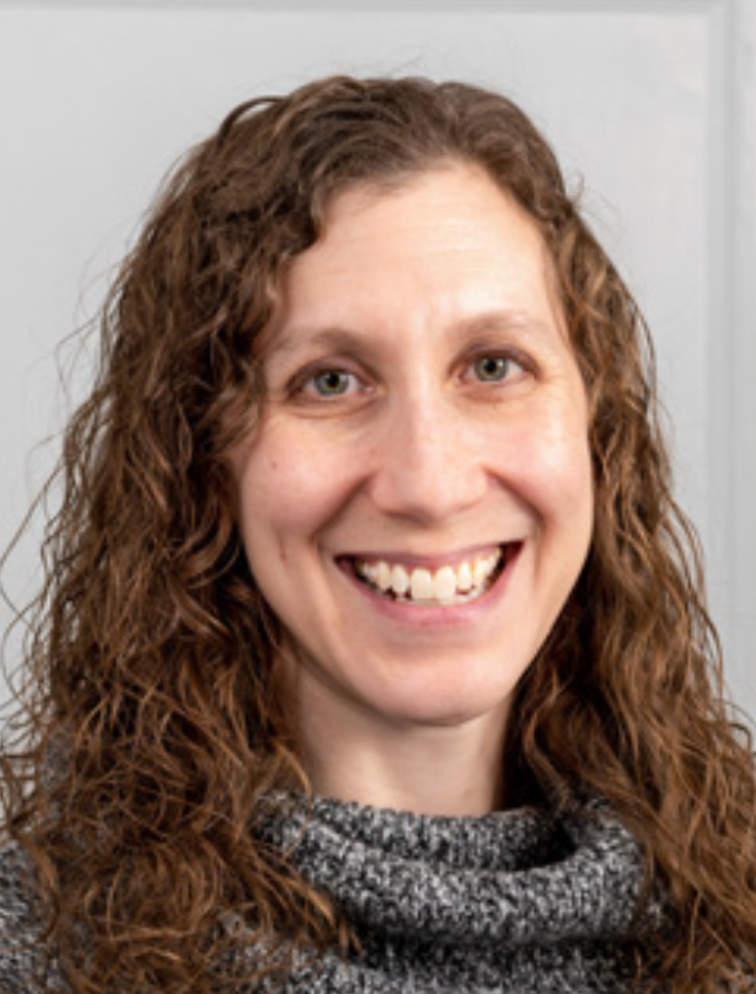A photo portrait of Wendy Freedman, a person with long brown hair. They are smiling at the camera.