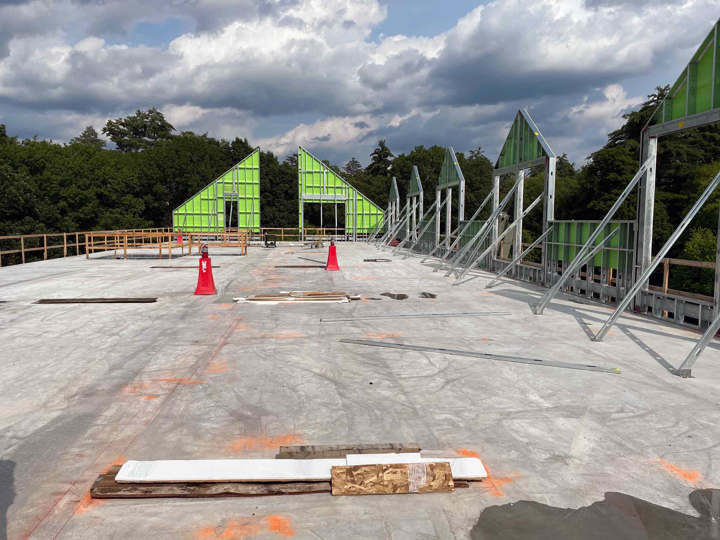 building in process of being constructed with green paneling and studs