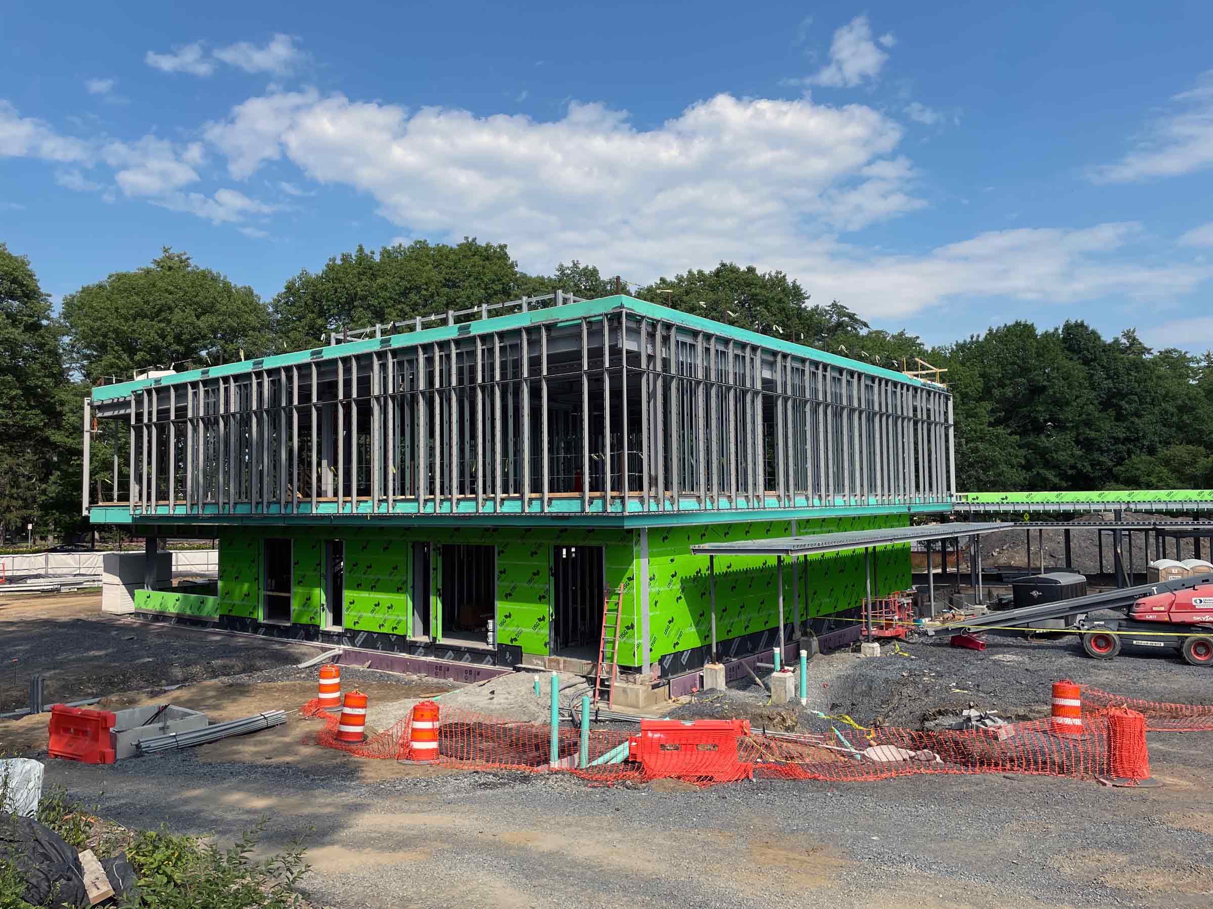 building in process of being constructed with green paneling and studs