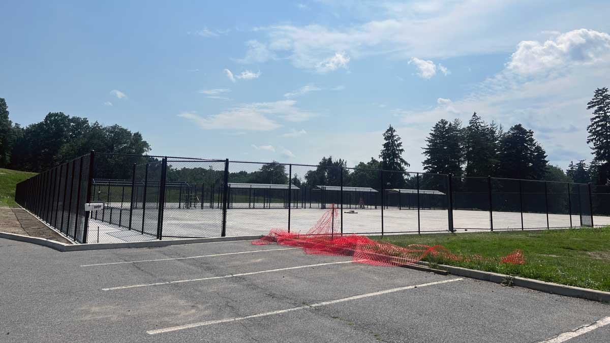 New Tennis Court from a distance with a black fence around it