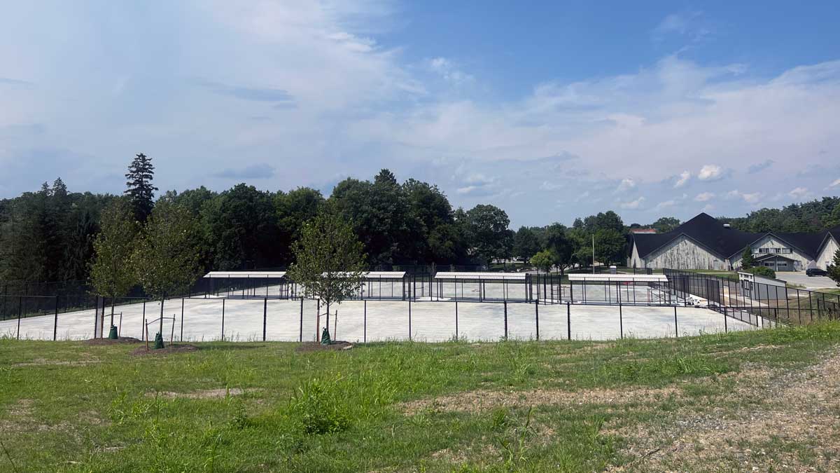 New tennis court with a black fence around it from a distance