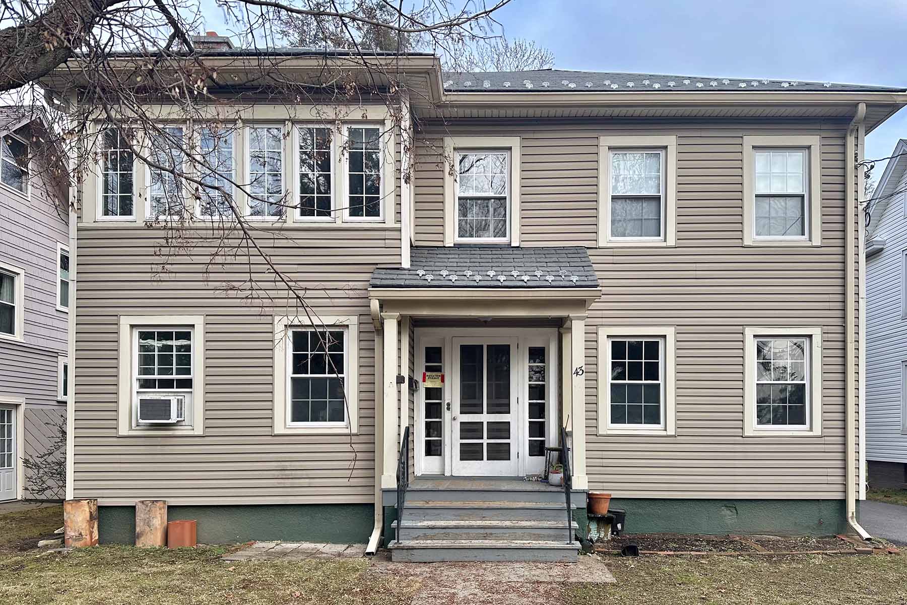Tan 2 story house with white trim.