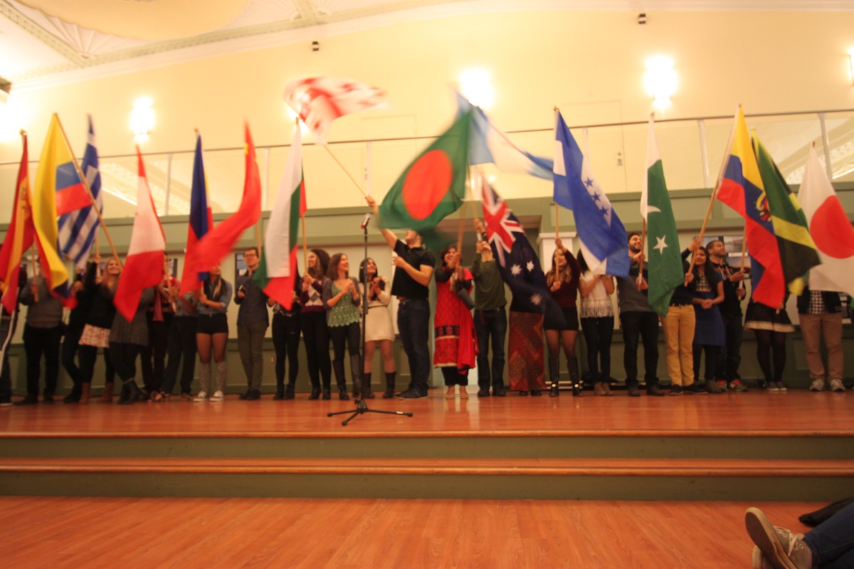 Group of people on a small stage holding flags of different countries.