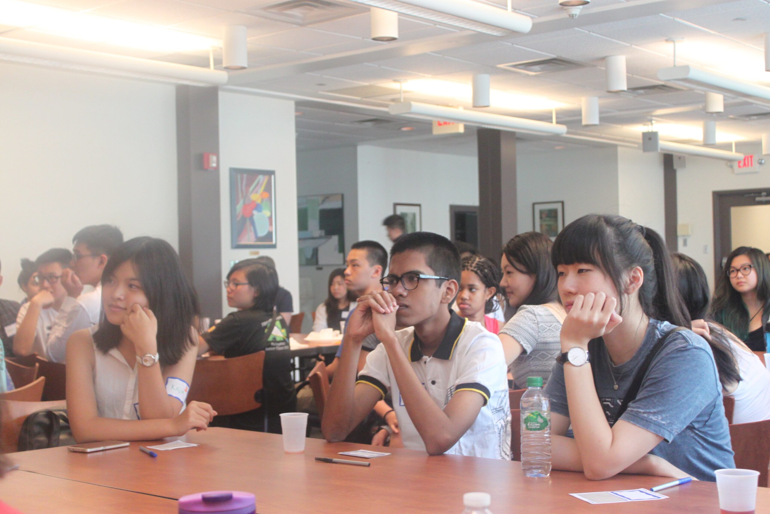Students sitting at tables in a large room.