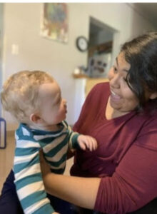 A person holding a toddler and smiling.